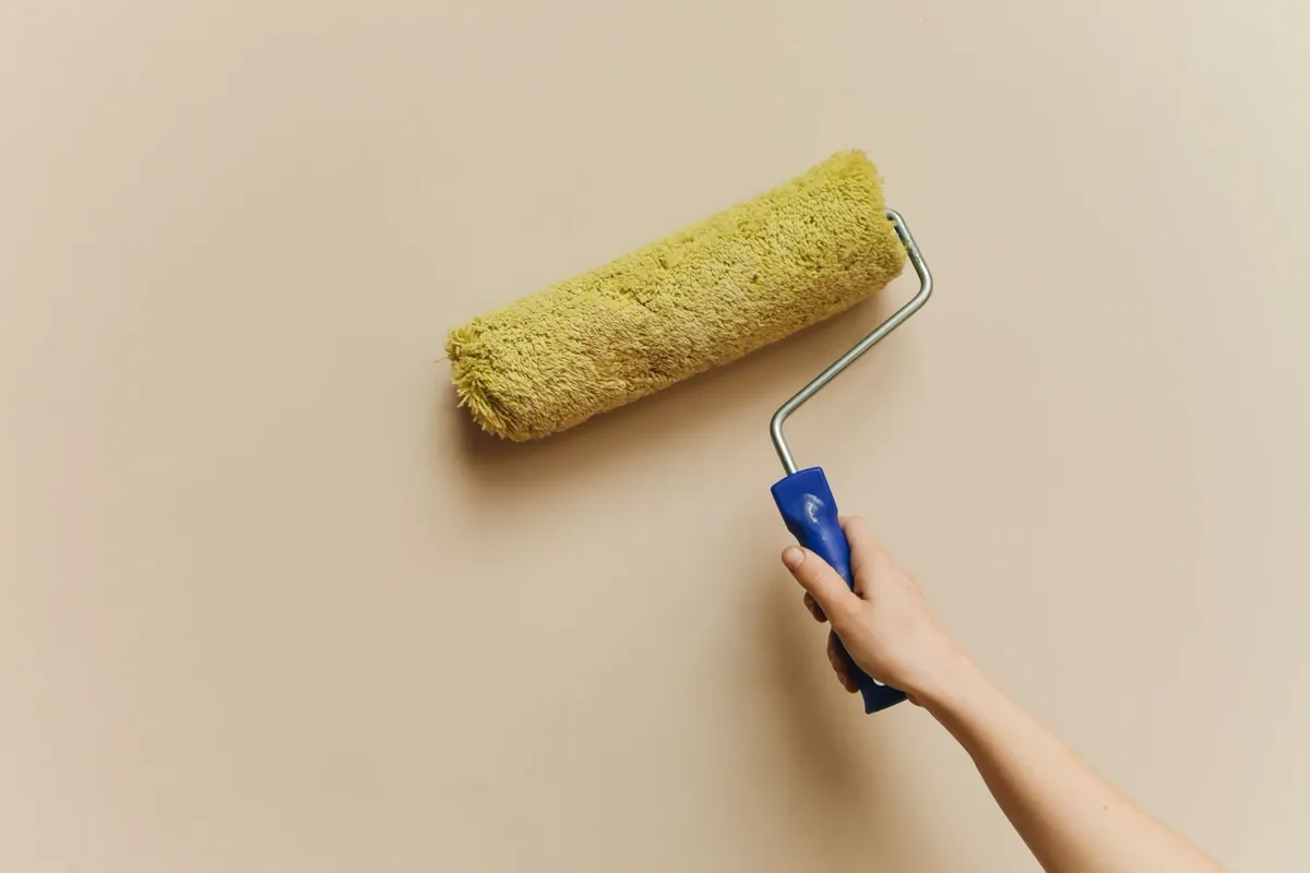 Paint roller applying fresh white paint to an interior wall