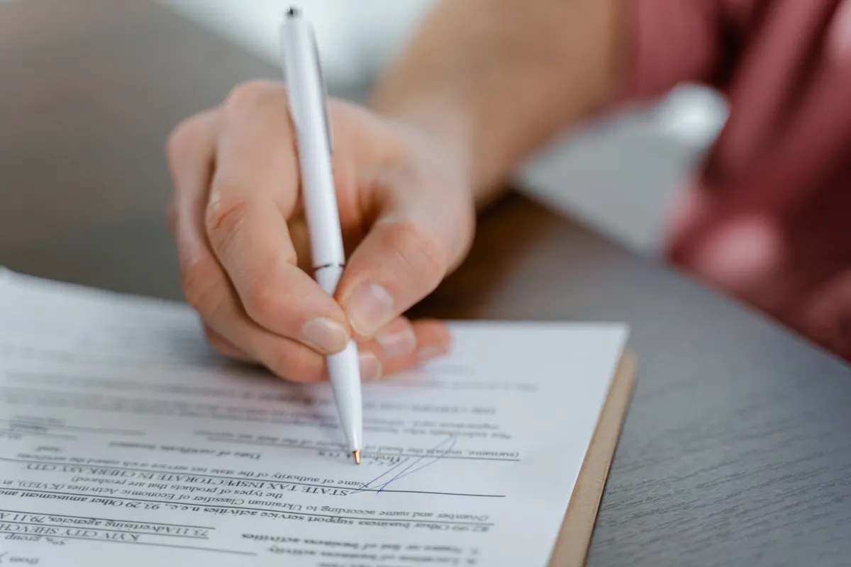 Hand signing a printed agreement with a ballpoint pen
