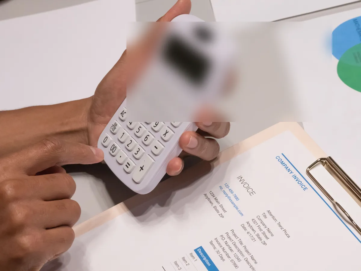 Hands using a calculator beside a printed invoice
