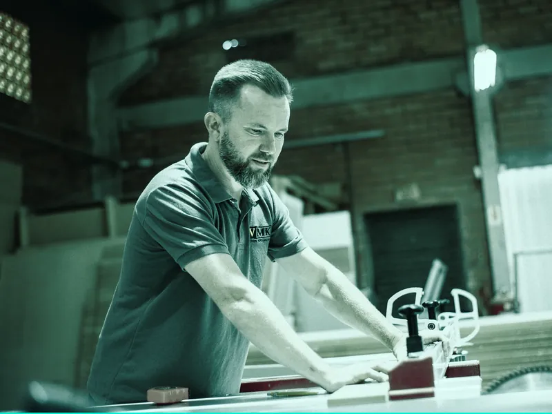 Carpenter cutting timber on a table saw in a workshop