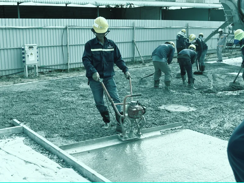 Concreters levelling a freshly poured concrete slab on a building site