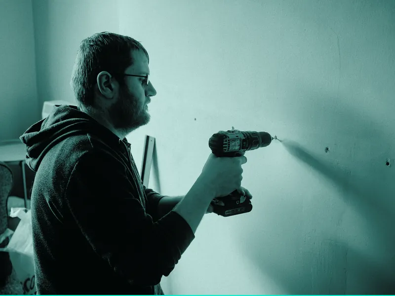 Handyman drilling into an interior wall during a home repair